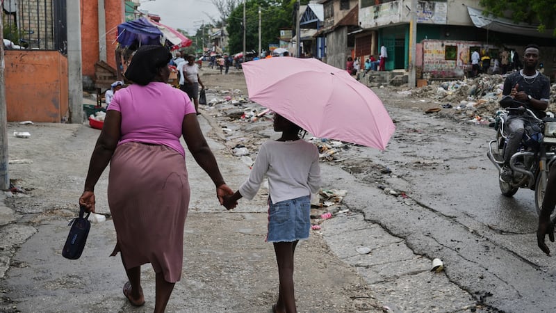 Una mujer camina de la mano con una niña con paraguas bajo una suave lluvia, el 23 de octubre...