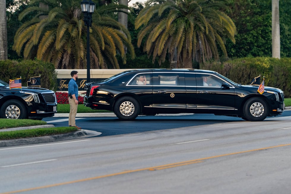 El presidente Donald Trump saluda desde su limusina al salir del Trump International Golf...