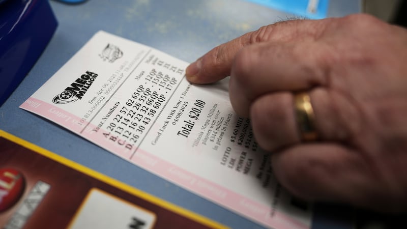 Pete Gruber points a Mega Millions lottery ticket after he purchased at Mares Mart in Chicago,...